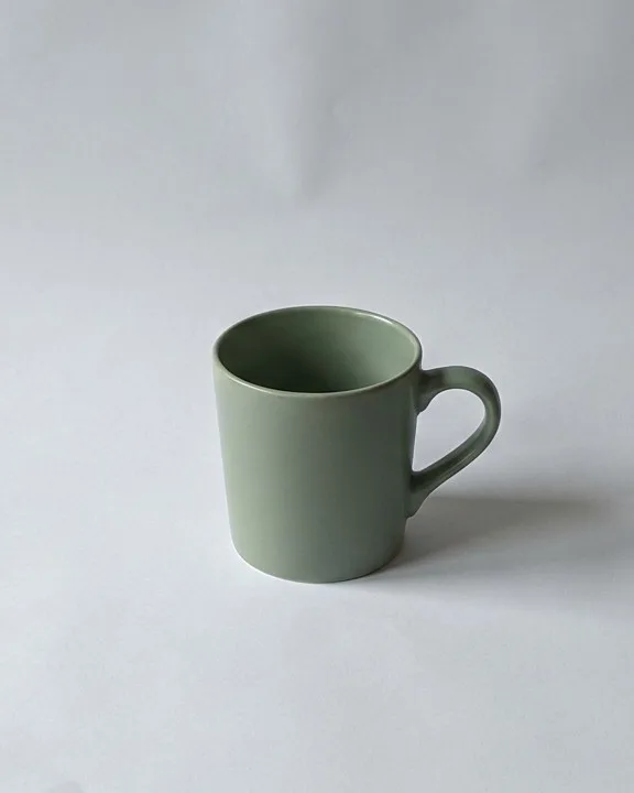 Sage green ceramic mug on a white paper sweep background