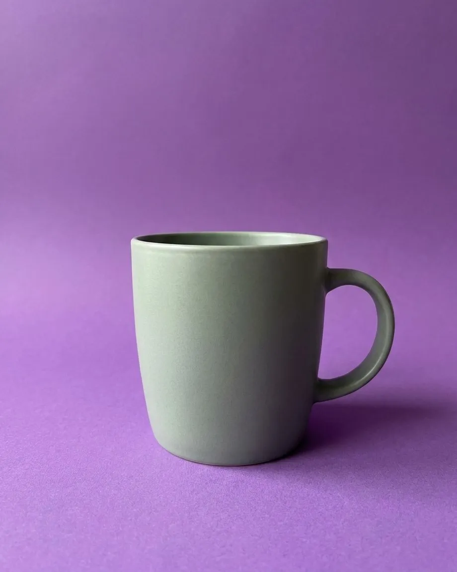 Sage green ceramic mug on a purple colored backdrop